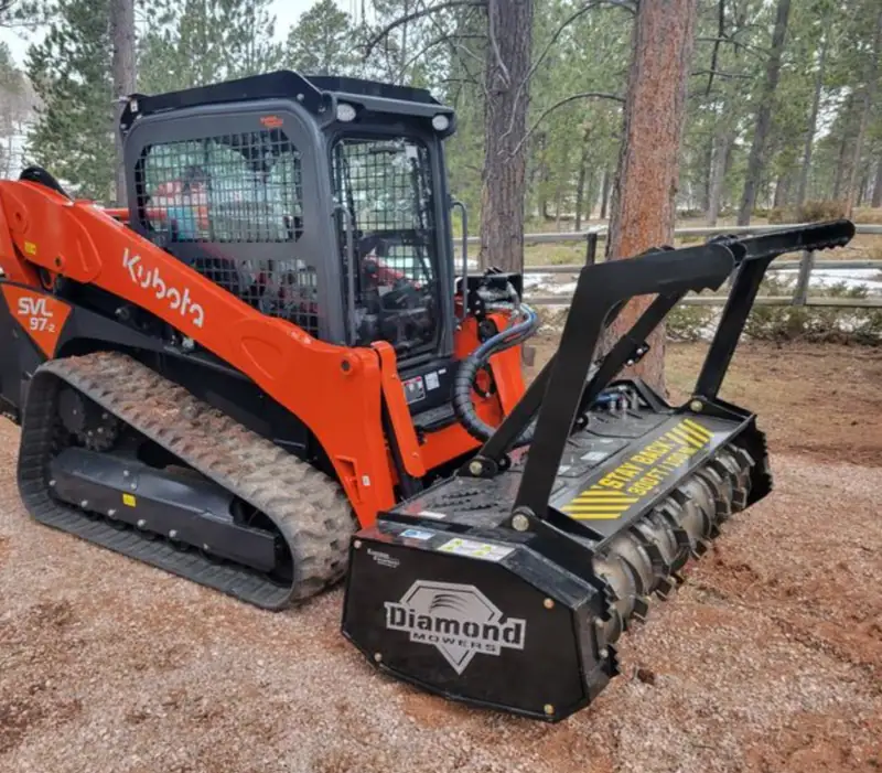 Our orange track loader parked on a pine straw job site
